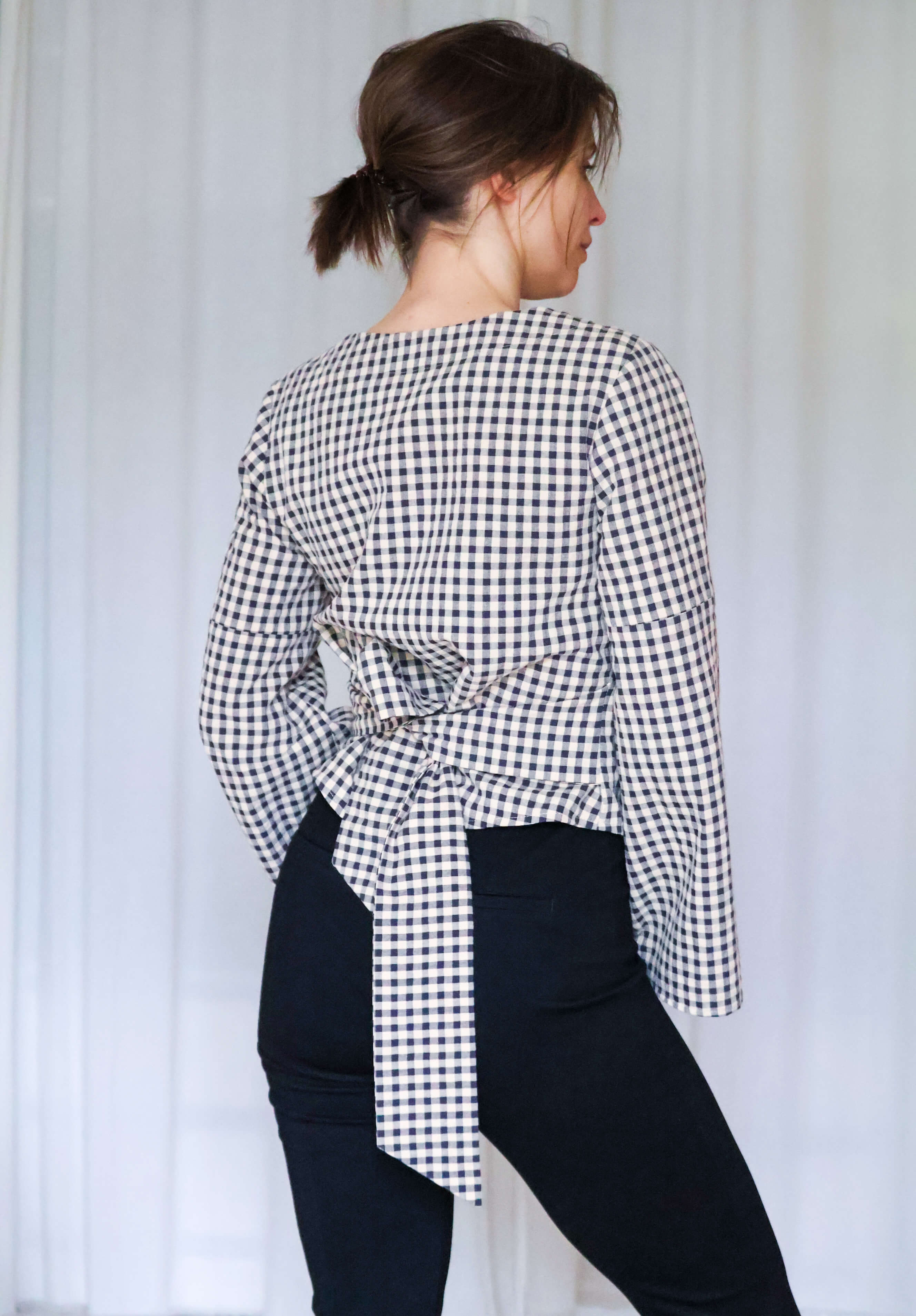 Rückenansicht der Paloma Wickelbluse mit gebundener Taille und leicht ausgestellten Ärmeln.